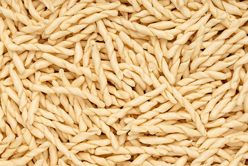 Macro photography of raw pasta strozzapreti, macaroni; twisted noodles; durum wheat semolina;...