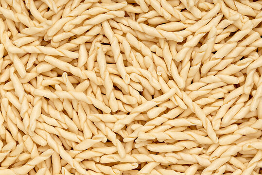Macro photography of raw pasta strozzapreti, macaroni; twisted noodles; durum wheat semolina; traditional italian food 