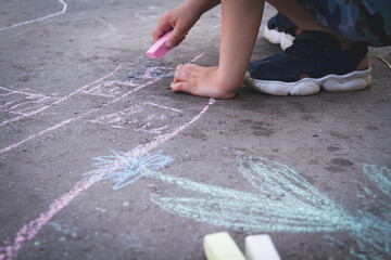 Children draw with chalk on the road. Children's creativity on the street. Entertainment in nature.