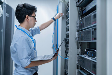 Fototapeta premium Computer engineer is setting up network in server room,Systems Maintenance Technician,Male engineer working in server room at modern data center
