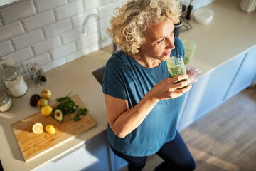 Woman drinking healthy homemade smoothie in the kitchen