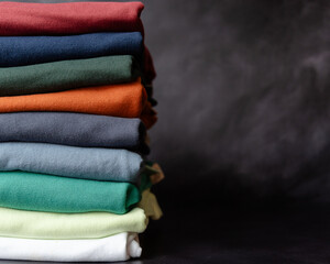 Colorful Folded Clothes Stack, Soft Textured Fabric in Pastel Shades for Fashion, Laundry, or Textile Industry, Cozy, Neatly Organized Apparel in Layers on Dark Background, Room For Content