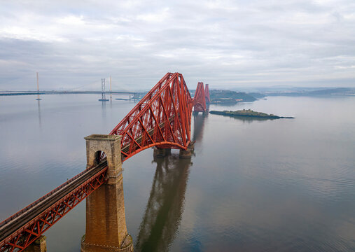 Aerial view of the iconic Forth Rail Bridge over the River Forth with reflections in the water, Queensferry, United Kingdom.