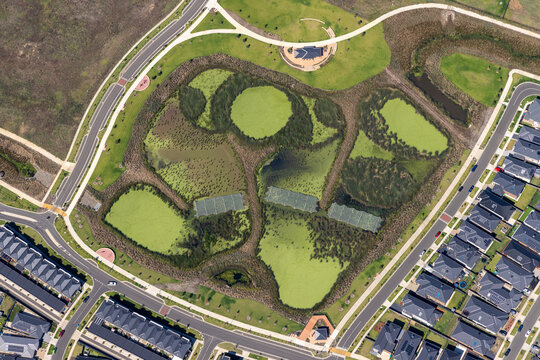 Aerial view of beautiful creekside park with ponds and residential area, Clyde, Australia.