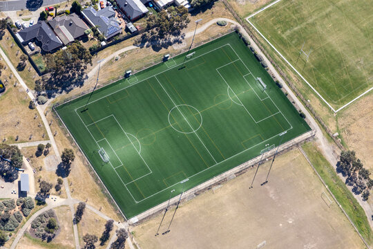 Aerial view of vibrant soccer field surrounded by residential houses and lush trees, Hoppers Crossing, Australia.