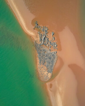 Aerial view of Nullagine River flowing through a beautiful coastal landscape with sandy beach and blue ocean, Cossack, Australia.