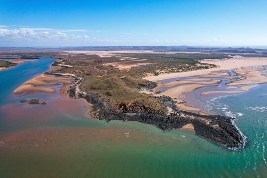 Aerial view of the beautiful coastline with sandy beach and tranquil Nullagine River, Cossack, Australia.
