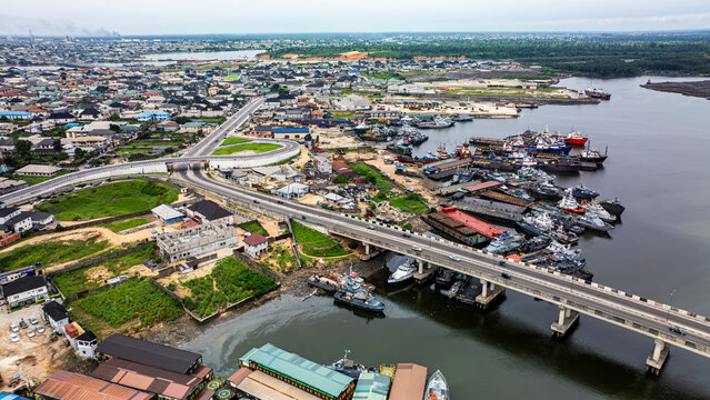 Aerial view of alcon bridge over the river with boats and buildings in a scenic urban landscape, Golf Estate, Port Harcourt, Nigeria.