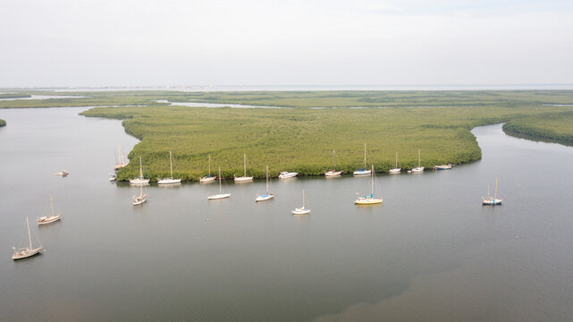 Aerial view of serene river with boats and mangroves, Sinchu Alagi, The Gambia.
