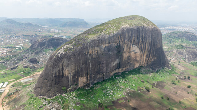 Aerial view of majestic Zuma Rock surrounded by serene valleys and vast landscapes, Suleja, Nigeria.