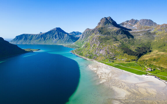 Aerial view of morpheus beach surrounded by majestic mountain range and tranquil blue water, Flakstad, Norway.