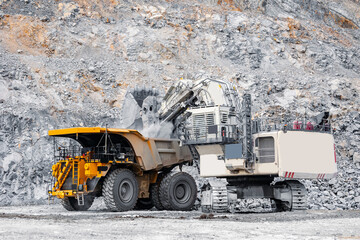 Industrial Excavator loads at gold, copper, iron ore to big yellow truck on Quarry Site. Work on Industry open pit mine