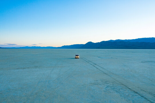 Aerial view of a serene and expansive dry lake bed at dusk with a VW Vanagon in the Black Rock Desert, Black Rock City, United States.