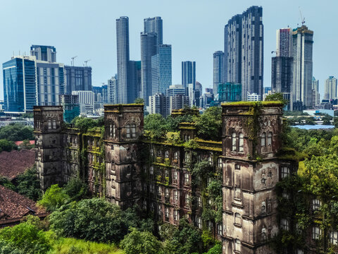 Aerial view of abandoned buildings and highrise skyscrapers surrounded by overgrown vegetation, Curry Road, Mumbai, India. - Powered by Adobe