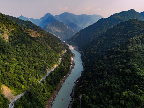 Aerial view of the serene Ganga River winding through majestic mountains and lush greenery, Rishikesh, India.
