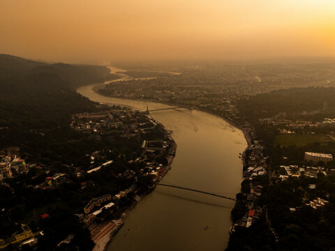 Aerial view of the scenic Ganga River with Ram Bridge and mountains at sunset, Rishikesh, India.