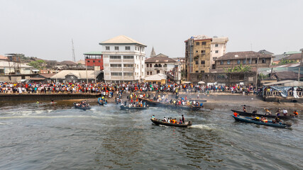 Aerial view of the vibrant Pokudoku Festival with colorful boats and a lively crowd along the riverbank, Abonnema, Nigeria.