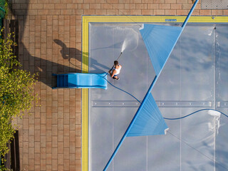 Aerial view of a public pool with a blue slide and cleaning worker during summer, Wedding, Germany.