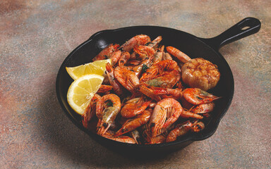 Fried shrimps, in a cast-iron pan, shrimps for beer, in a newspaper, on a gray table, there are no people,