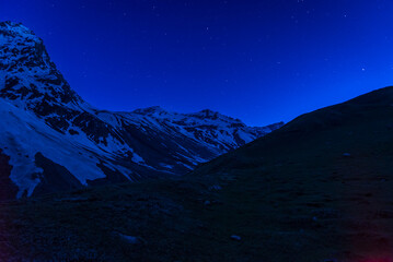 Starry night and Milky way galaxy long exposure grainy night shoot at Rupin pass trek campsite snow cladded mountains of Himalayas in Himachal Pradesh, India.