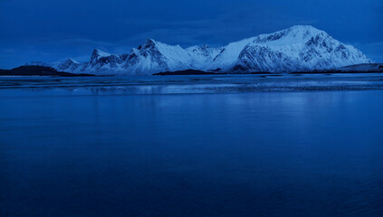 Polar Night. Panoramic view of small islets and snow-covered mountains along pristine beach. Lofoten Islands, Northern Norway. © Iraj Nouri