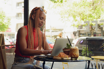 Young Woman working in cafe with laptop while having breakfast