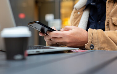 Fototapeta premium Freelancer working remotely using smartphone and laptop in cafe
