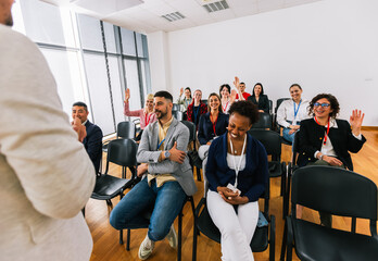 Male CEO standing in front of a multiracial group of colleagues and calls out someone to answer the question. Multimedia classroom with smart board.