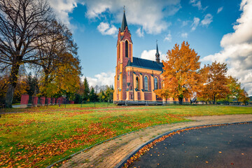 Attractive autumn view of red brick Church of St. Stanislaus the Bishop, Poland, Europe. Moddy morning scene of Lutowiska village, Bieszczady County, Subcarpathian Voivodeship of  Poland.