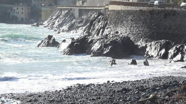 Waves crashing against the rocky cliffs of the coast on a sunny day, along the Via Aurelia from Genoa Voltri towards Vesima