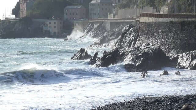 Waves crashing against the rocky cliffs of the coast on a sunny day, along the Via Aurelia from Genoa Voltri towards Vesima