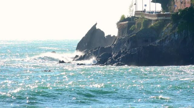 Waves crashing against the rocky cliffs of the coast on a sunny day, along the Via Aurelia from Genoa Voltri towards Vesima