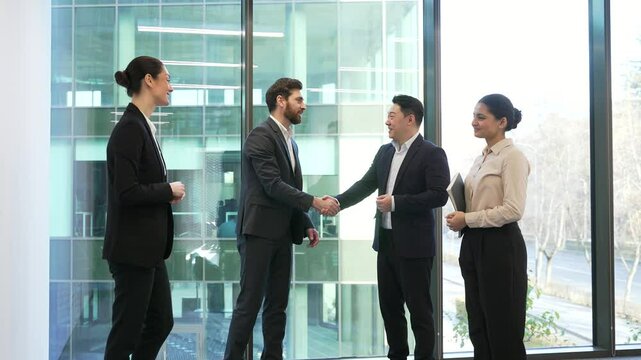 Colleagues communicate have a friendly chat during a coffee break. Group employees team business people coworkers having fun discussing project standing in office laugh indoor familiar cheerful joyful