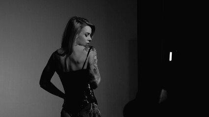 Blonde with a beautiful figure in a black patent leather bodysuit posing in a studio. Studio...