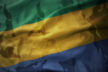 colourful waving flag of gabon on the old army khaki texture background. military concept.