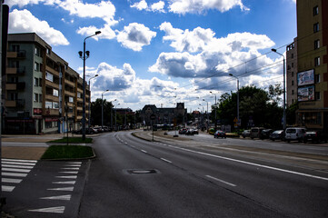 Empty road with pedestrian crossing on city streets under blue sky with parking lots for cars.