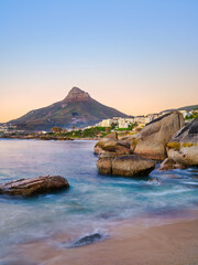 Obraz premium Sunset view of Lion's Head and Camps Bay behind the boulder at Beta Beach, vertical shot, Cape Town, South Africa