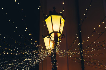 Twinkling lights illuminate a charming street during a festive evening in a vibrant city