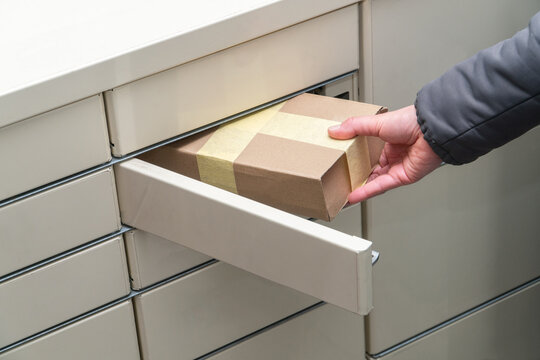 Female hand puts a parcel into post terminal machine.