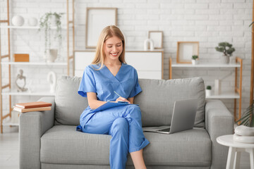 Female medical intern with laptop on sofa in living room