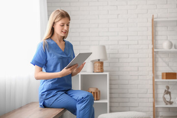 Female medical intern sitting and holding tablet in room