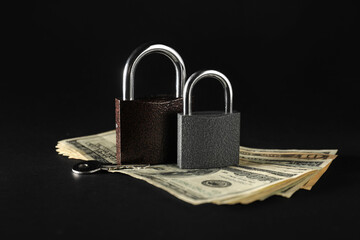 Padlocks with money and key on black background