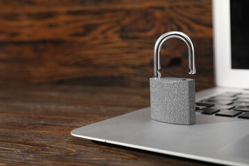 Padlock with laptop on wooden background