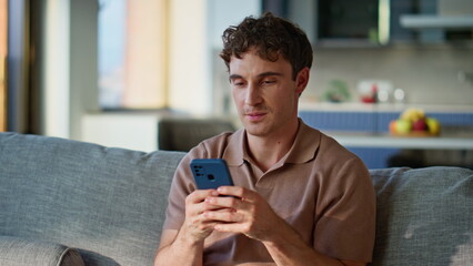 Relaxed man answering sms sitting sofa cozy living room closeup. Handsome guy
