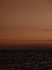 Tranquil brown sunset over ocean horizon with gentle waves