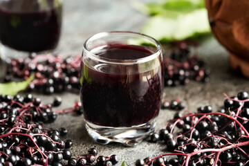 A cup of black elderberry syrup with fresh elder berries