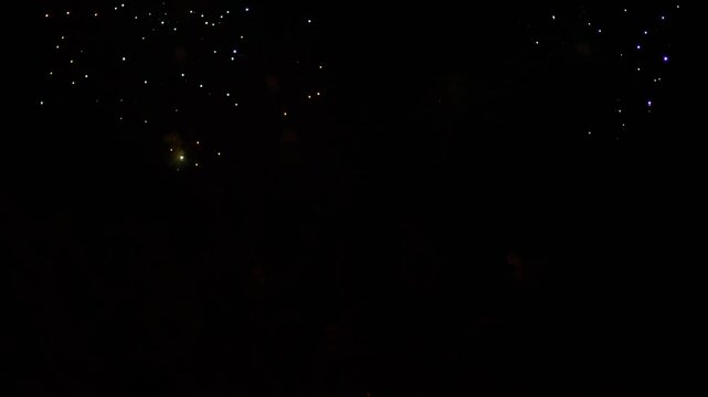 Gold and purple blue green sparks scatter fireworks on the black night sky. General plan