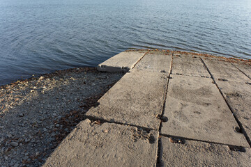 Ugly wharf and dock made of rough concrete blocks. Coast and shore of sea, ocean, dam or water...