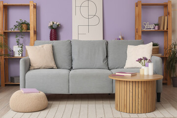 Comfy sofa, coffee table and shelving unit in stylish interior of living room