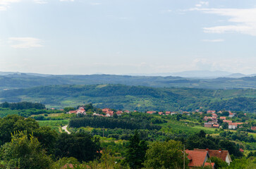 Fototapeta premium City suburb with red roofs of houses in a picturesque landscape under the blue sky on a summer day